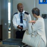 Commuter getting a bag checked from airport security officer in airport terminal
